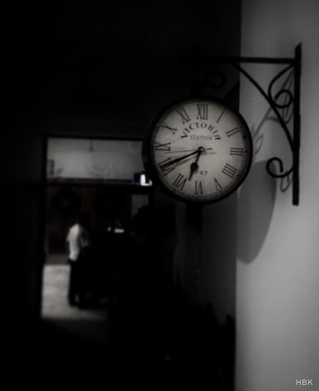 Black-and-white photograph of a wall-mounted station-style clock