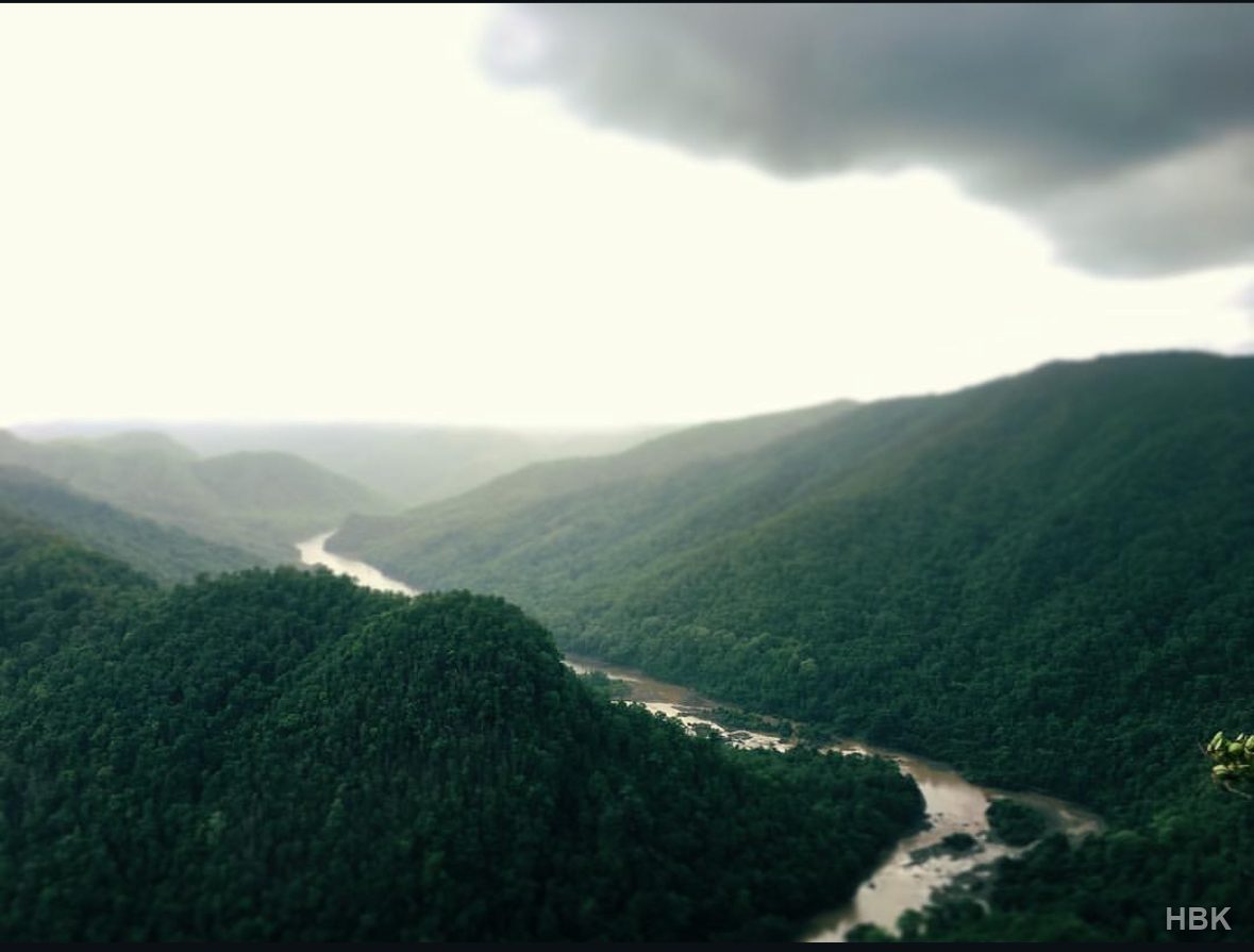 River winding between forested hills beneath cloudy skies