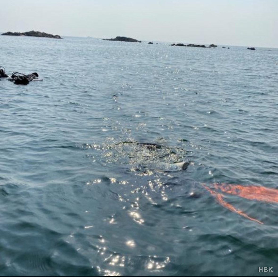 Scuba diver entering the water, with fins visible near the surface
